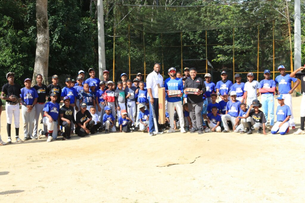 Diógenes De la Cruz y Esmeily Martínez, del Departamento de Educación de la DCNB hacen entrega de utilerías al dirigente de la Liga FDP , Santos Reynoso durante la visita que realizaron en la Cuchilla, Villa Altagracia.